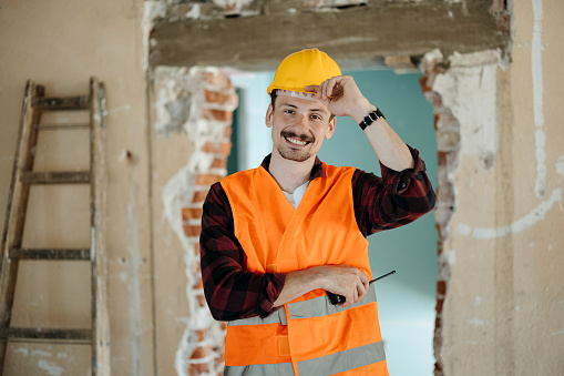 Construction worker standing at building site and looking at camera