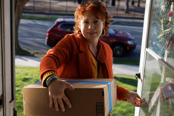 istock Home delivery box. Smiling ginger woman accepting parcel at doorstep 2133548607