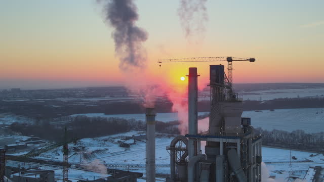 Aerial view of cement factory with high concrete plant structure and tower crane at industrial production area in evening. Manufacture and global industry concept
