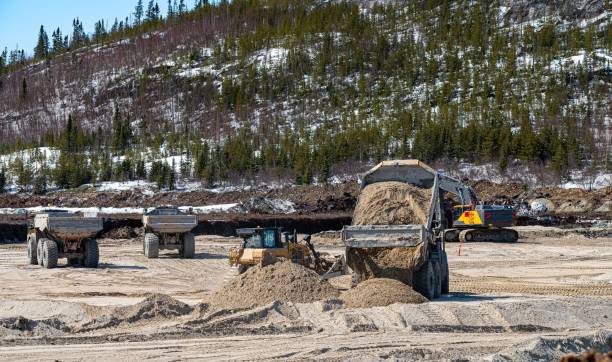 istock Three dump trucks with a bulldozer and an excavator 2133603940