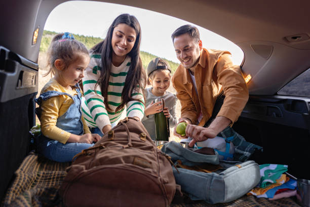 istock Caucasian parents with daughters packing stuff for a picnic into backpack, from the car trunk 2133615673