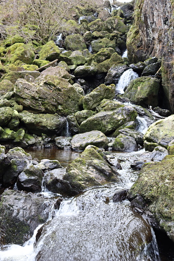 Series of waterfalls falling over moss covered boulders