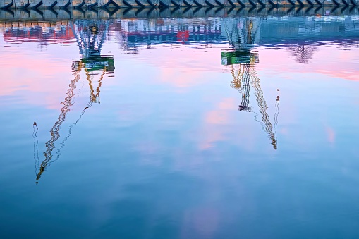 Reflection of port cranes in the water. Seaport with cranes in pastel colors.