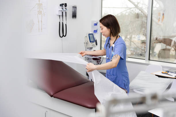 istock Female nurse rolls out fresh paper liner for examination table 2133632574