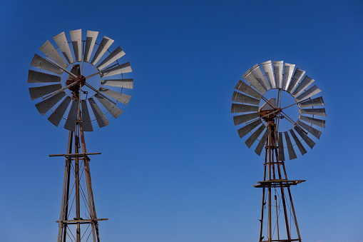 Turbine section of two old style windmill with blue sky as background. background.