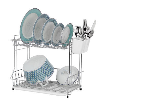 Drying rack with clean dishes on white background, stainless steel cutlery isolated with space for text