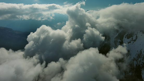 Flying through beautiful white fluffy clouds between high rocky mountains. Dolomites Alps, Italy