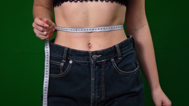 Woman Measures Her Waist After Losing Weight with a Measuring Tape