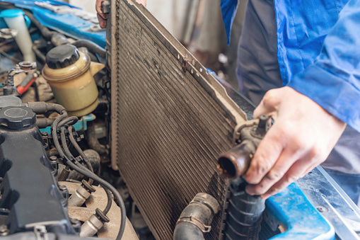 A man replaces an old broken radiator in a car with a new one.