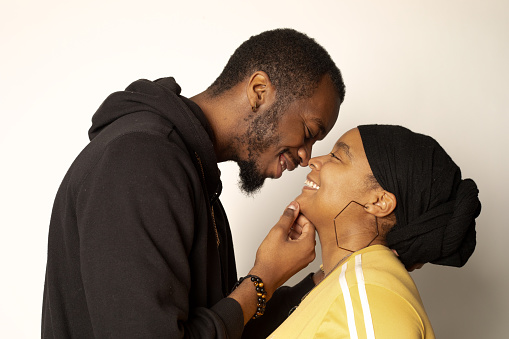 African-American couple smiling while facing each other, man is holding woman's chin