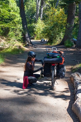 Woman adjusting a saddlebag on her bicycle during a trip through the Bariloche region of Argentina