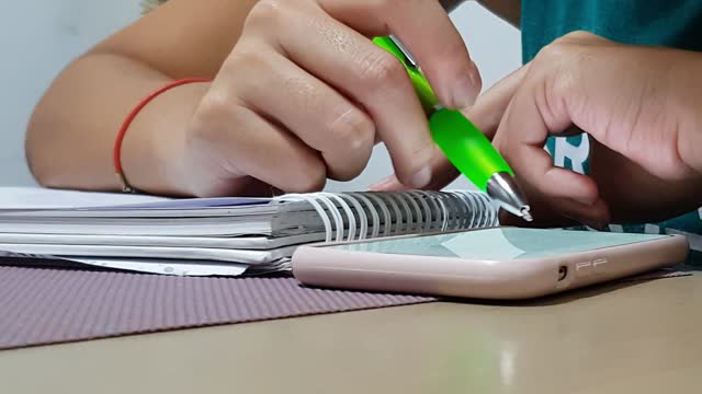 Student taking notes with smartphone nearby