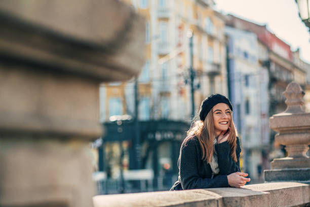 Portrait of Happy young woman on the city street. Portrait of beautiful young woman in warm winter knitted clothes, woolen scarf, hat and coat enjoying sunny winter day.