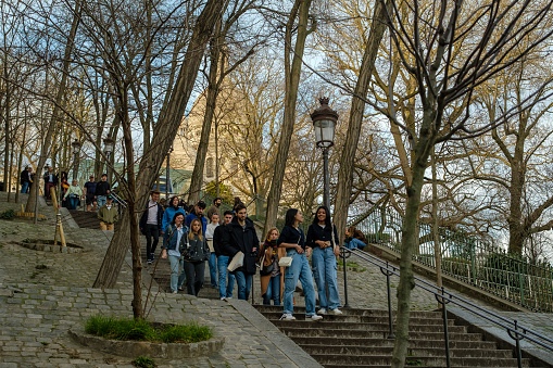 Paris, France - February 17, 2024 : View of tourists walking up and down the picturesque staircases with the lanterns in the Montmartre area in Paris France