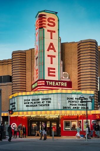 People walk past the landmark State Theater in downtown Ann Arbor, Michigan, USA in the evening.
