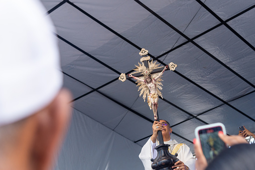 Salvador, Bahia, Brazil - December 29, 2023: Catholic priest raises the image of Jesus Christ during mass at the Senhor do Bonfim church in the city of Salvador, Bahia.