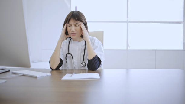 istock Doctor with headache at desk 2133823451