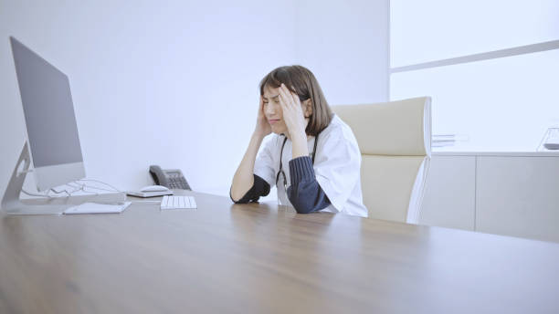istock Doctor with a headache at desk 2133823467
