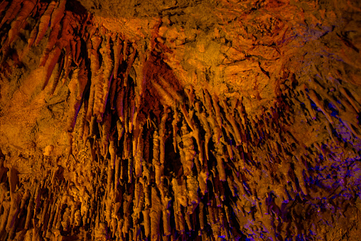 Journey through a vibrant cave adorned with colorful walls, stalactites, and stalagmites, revealing the underground beauty of nature's geological wonders.