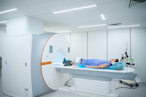 Patient in noise-canceling headphones and coil placed around knee lying supine on MRI table