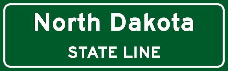 North Dakota state line road sign, white letters on green background