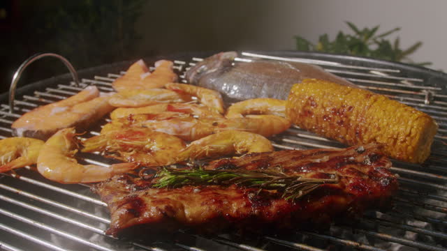 Chef cooking shrimps with oil and spices on grill close-up. Prawns on fire throwing them on pan. Dorado and salmon fish steak on frying grill. Restaurant Food concept. Sea food barbecue.