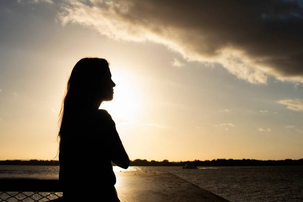 Silhouette of a woman on the banks of Lake Guaiba in Porto Alegre looking at a storm cloud in the late afternoon