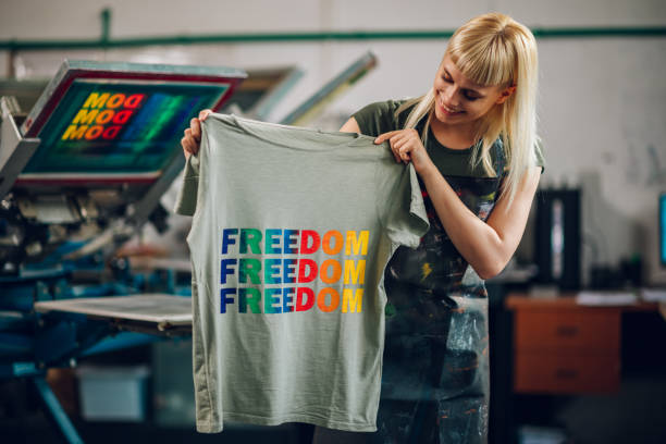 istock Happy print shop worker showing screen printed t-shirt at camera. 2133994764