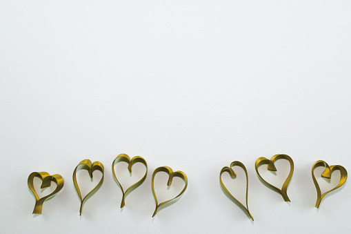 Heart shape made of gold ribbon on white background with copy space.