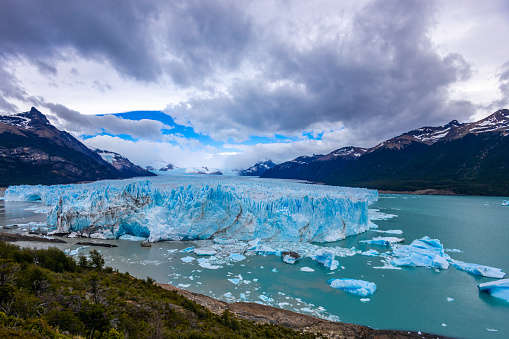 Perito Moreno sparkling glacier ice in Patagonia, Argentina Los Glaciers National Park near El Calafate. Bule ice South America mountains patagonian glacier on a sunny day with clouds. Glacier serac falling in lake