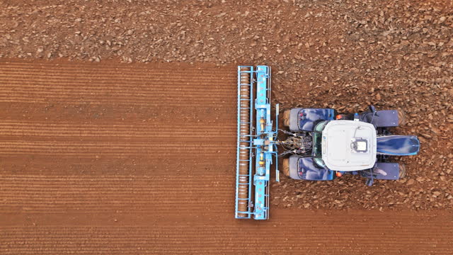 AERIAL Drone Top Down Shot of Tractor Preparing Field for Sowing in Village