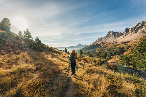 Rear view of Female hiker trekking on hiking trail in Massif Des Cerces of Claree Valley during autumn at French Alps, France