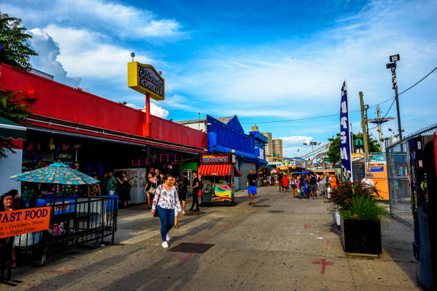New York City, New York, USA - July 10, 2015: Sunset view of historic Coney Island boardwalk in Brooklyn with amusement park rides and people visible.