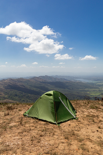 Green camping tent on top of mountain during dry season or summer with beautiful blue sky. Enjoying time in the outdoors. Trekking concept.