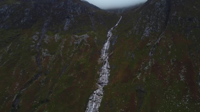 Slow motion drone landscape of Ben Nevis Waterfall geological formation water stream fall through wet humid mountain
