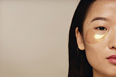 Asian Woman With Collagen Eye Patches Half Face Shot