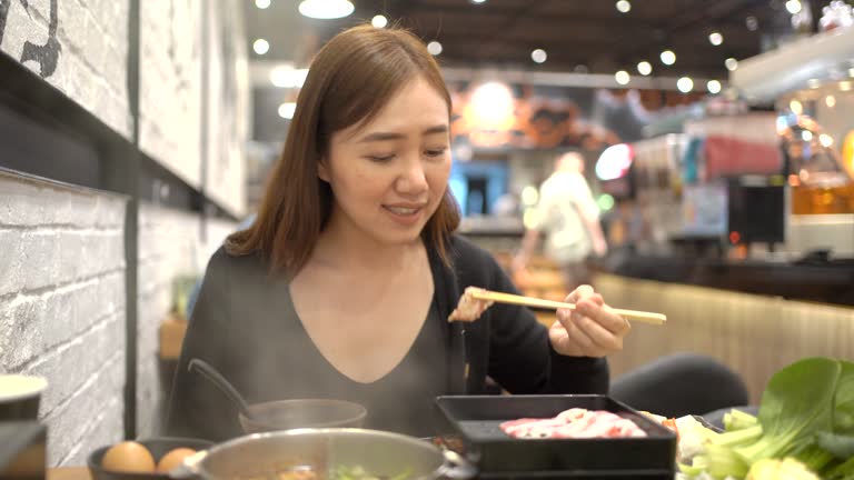 Woman eating Shabu Shabu in the Asian restaurant.