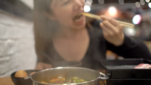 Woman eating Shabu Shabu in the Asian restaurant.