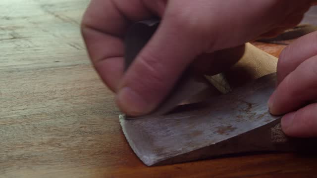 Close up: Fine grit sandpaper is used to clean rust off old axe head