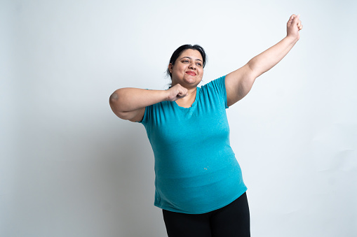 Overweight indian woman cheering with open arms, dancing isolated over white background. Plus size female carefree. Healthcare Fitness concept. Copy Space