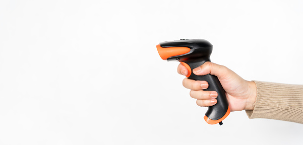 A person is holding a black and orange barcode scanner. Concept of technology and productivity