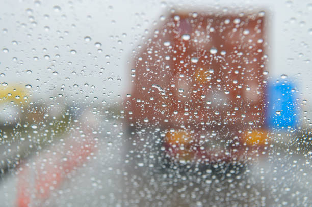 Truck running ahead on a rainy day\nAt road junctions, raindrops make it difficult to see the truck ahead through the windshield.