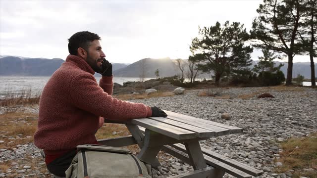 Contemplative Man Resting at Picnic Table in Serene Landscape