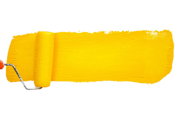 Male decorator's hand holding a paint roller, renovating with yellow paint. DIY renovation project: man using a paint roller to apply yellow paint. Old refrigerator.