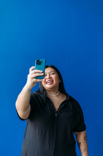 Woman video-calling her friends studio shot blue background