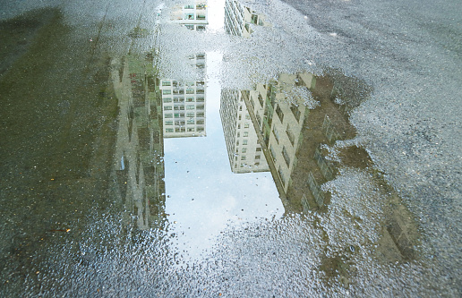 High buildings reflecting on the puddle after rain