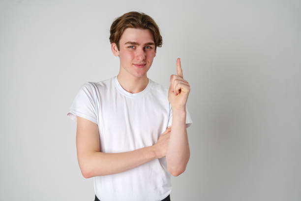istock Young Man Standing Against a Neutral Background With Raised Index Finger 2134660109