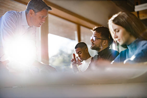 istock Mature teacher assisting his student on a class in the classroom. 2134665351