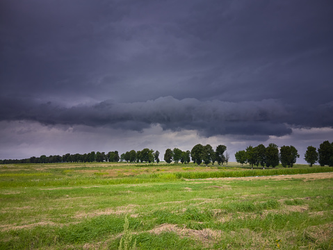 Storm dark clouds over the field with grass, a storm is coming