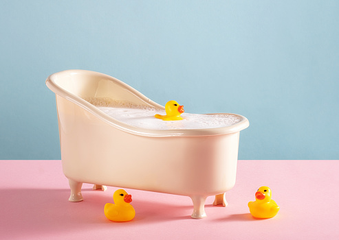 Bath with rubber ducks on pink and blue background.